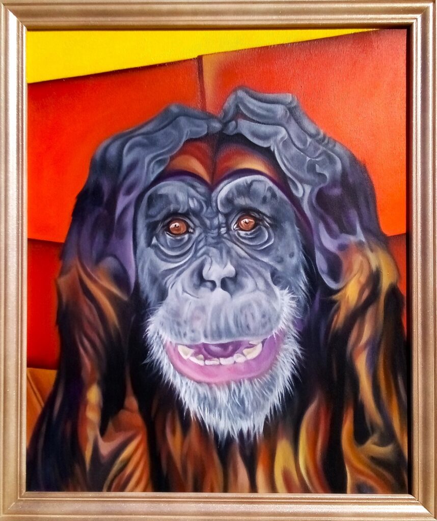 A colourful painting of a smiling chimpanzee with its hands forming a heart shape above its head. The background features vibrant shades of red, orange, and yellow. The frame of the painting is brown with a gold accent.